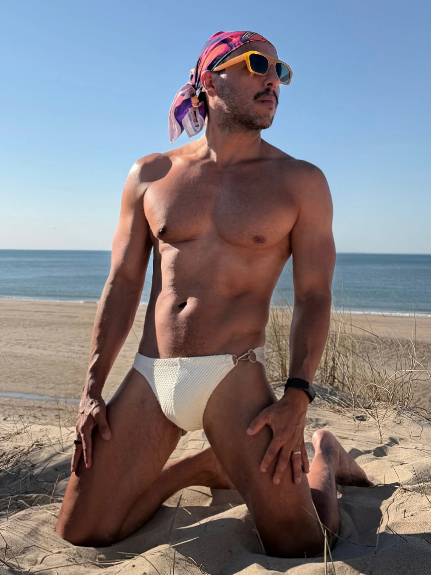 Latino sitting at the beach with a bandana around his head