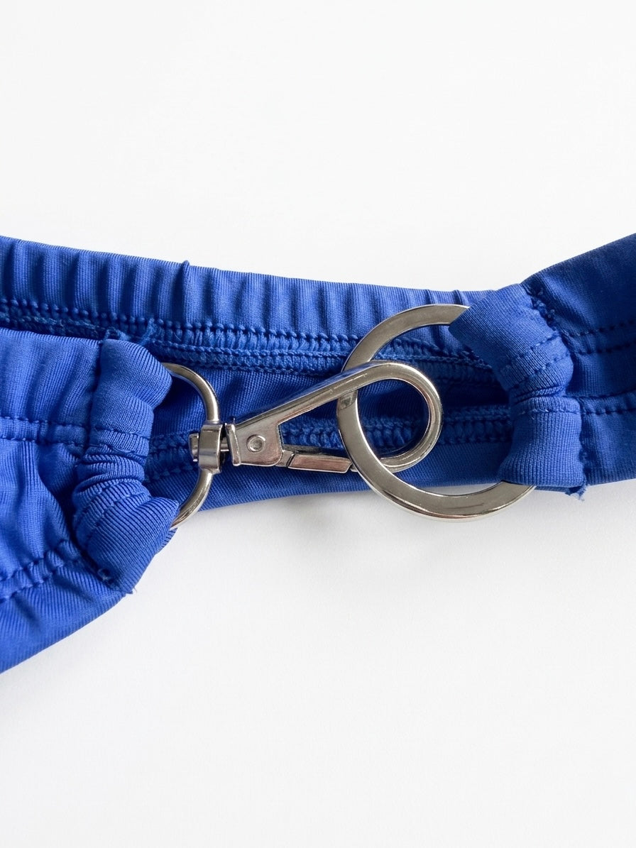 Close-up of a blue dog harness with a metal clip on a white background