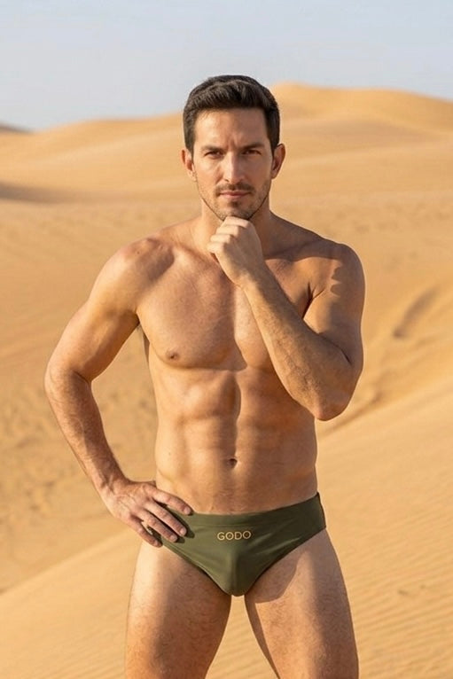 Man wearing green swimsuit with 'Godo' branding in a desert setting