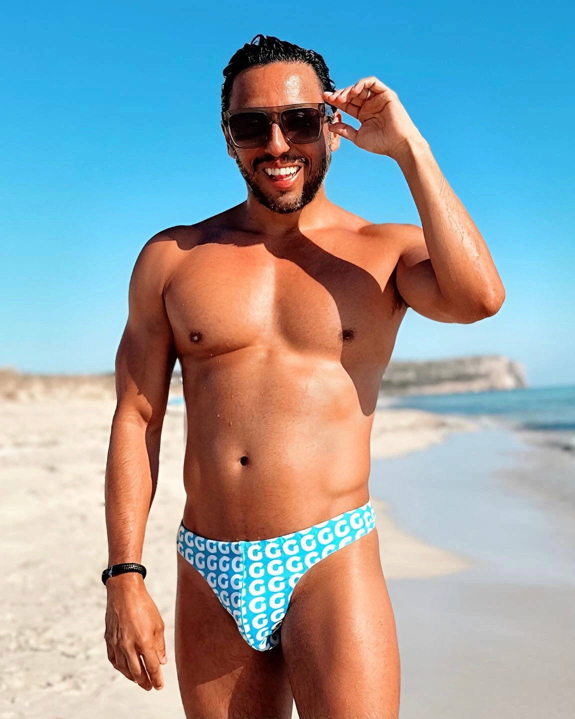 Man wearing a blue and white patterned swimsuit on a beach