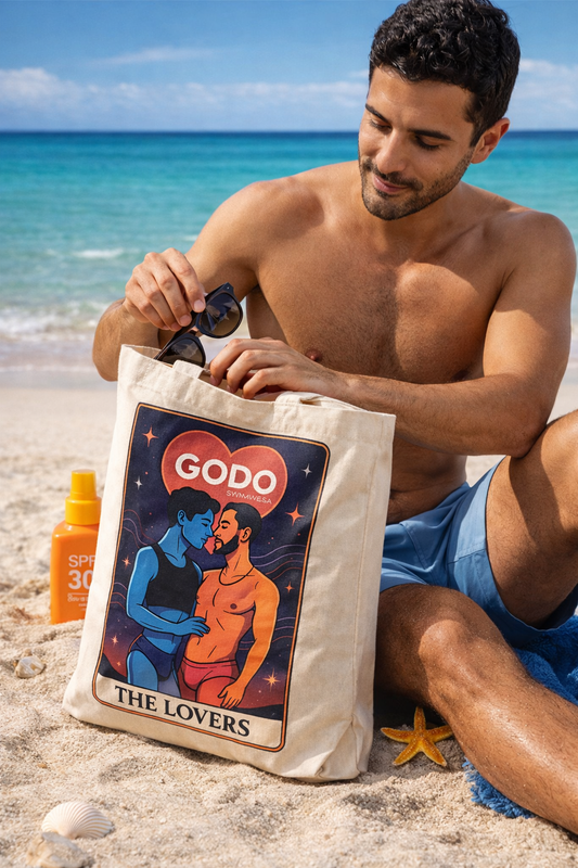 Man on a beach holding a tote bag with 'Godo' branding and design.