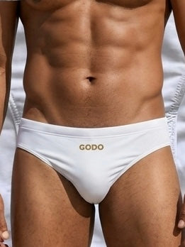 Man wearing white swimwear with 'Godo' branding on a neutral background