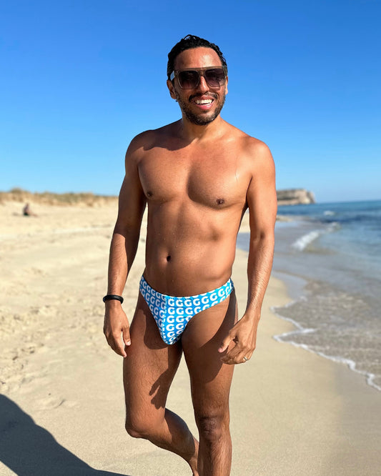 Man wearing a blue patterned swimsuit thong on a beach
